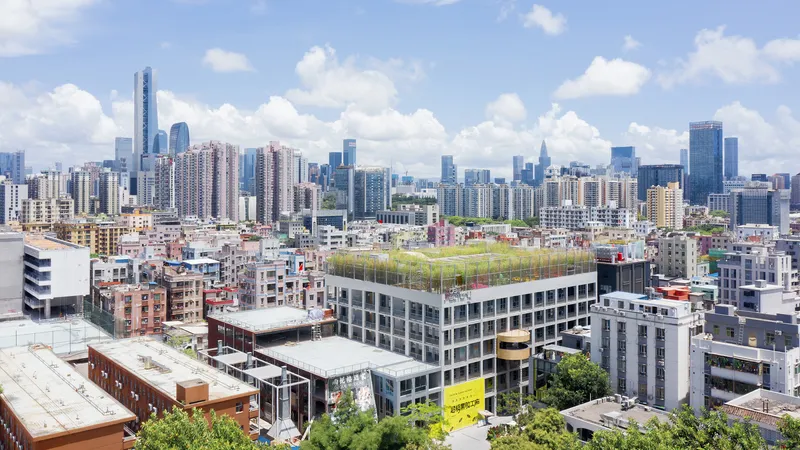 Rooftop green field on a rectangular building surrounded by dense urban fabric under scattered clouds