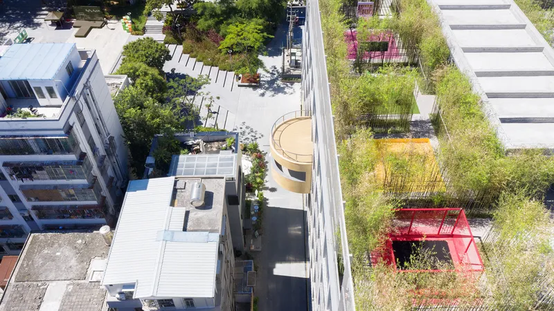 Aerial view of rooftop walkway with planted beds, circular timber pavilion, and red play structure