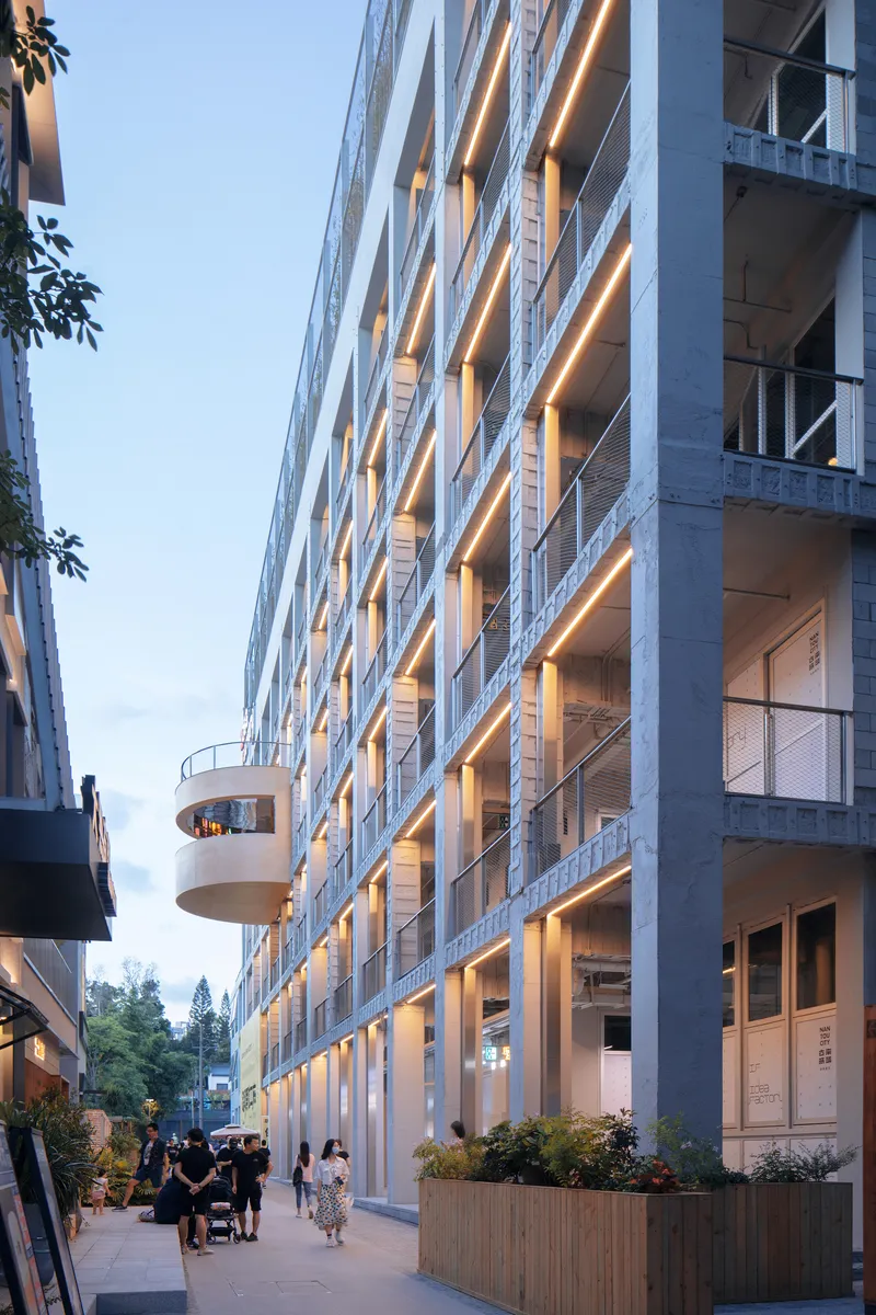 Street level view of the repeated horizontal slab edges with warm lighting at twilight