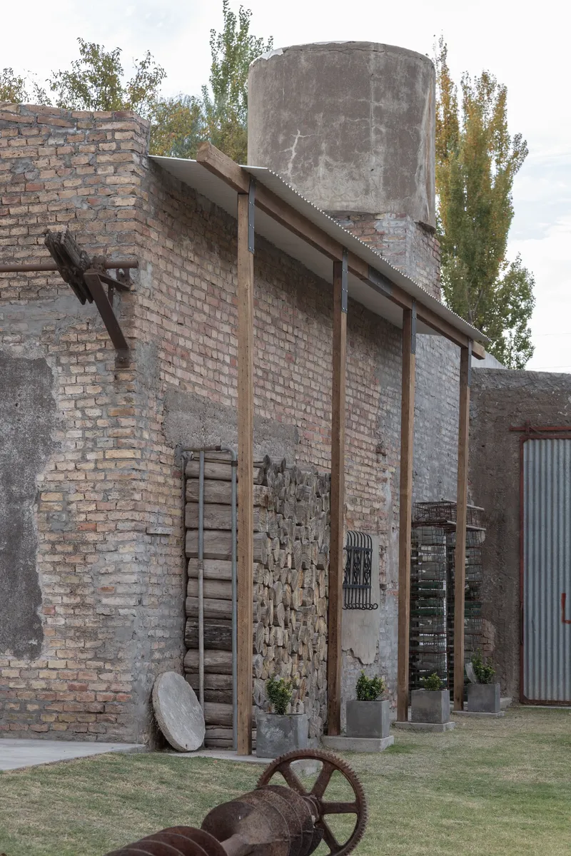Freestanding timber frame with slanted rafters anchored to the weathered brick wall and water tower beyond