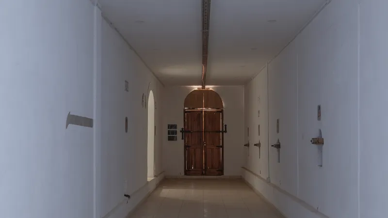 White plastered corridor with arched timber door and metal light fixture suspended from ceiling