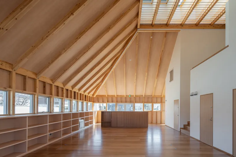 Interior space with exposed timber rafters, built-in plywood shelving along the walls, and a skylight overhead