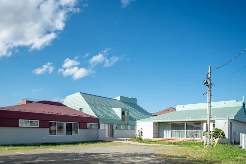 Cluster of gabled roofs in maroon and pale green metal under a blue sky with clouds