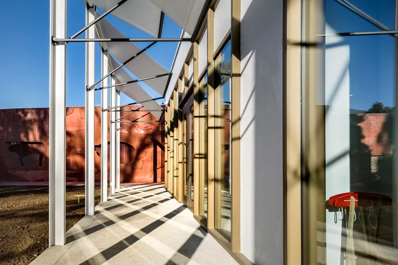 Exterior corridor with white steel columns and shadows falling across the polished concrete floor