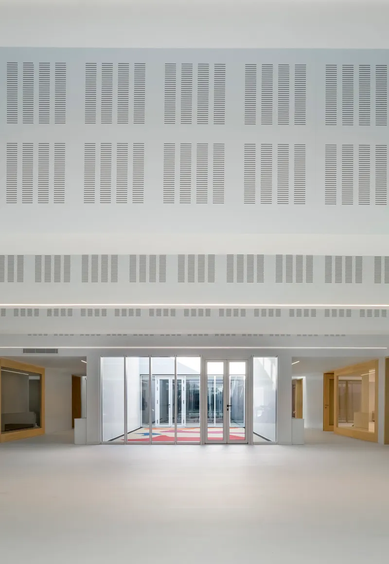 Interior lobby with glass entry doors facing a courtyard beneath a perforated acoustic ceiling