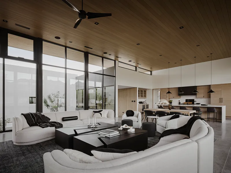 Living room looking toward kitchen with courtyard view through black-framed glazing on overcast day