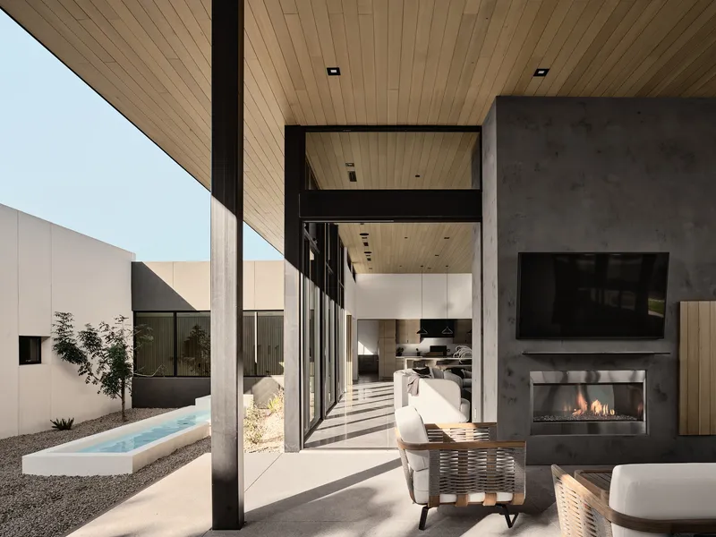Covered patio with timber ceiling, steel columns, and dark fireplace wall overlooking courtyard pool