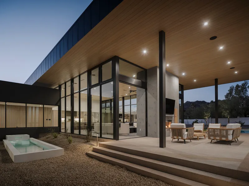 Covered terrace with timber soffit and black steel columns overlooking pool at dusk