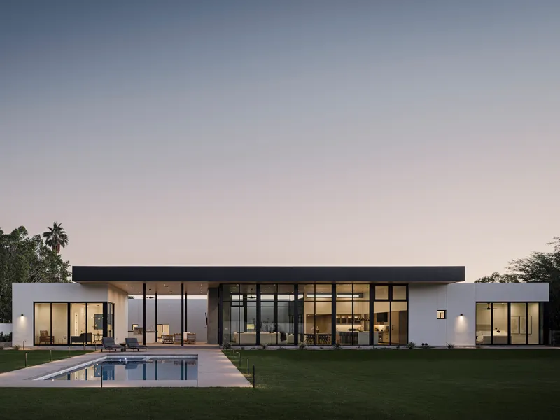 Garden elevation showing glass-walled living pavilion and swimming pool at dusk