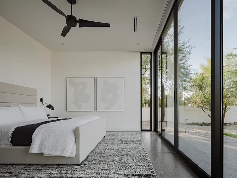 Bedroom with corner glazing opening to gravel courtyard and native desert trees