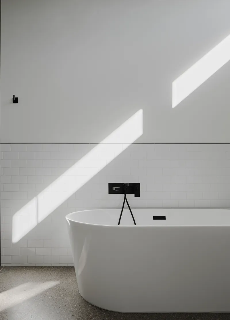 Freestanding white bathtub with black faucet under diagonal morning sunlight