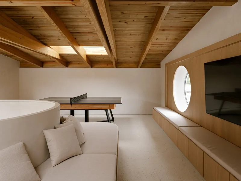 Upper level room with exposed timber ceiling beams, a circular window and built-in bench seating