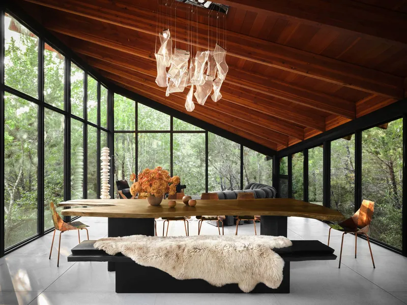 Dining room with floor-to-ceiling glazing, wood plank ceiling, and pendant light fixture above table