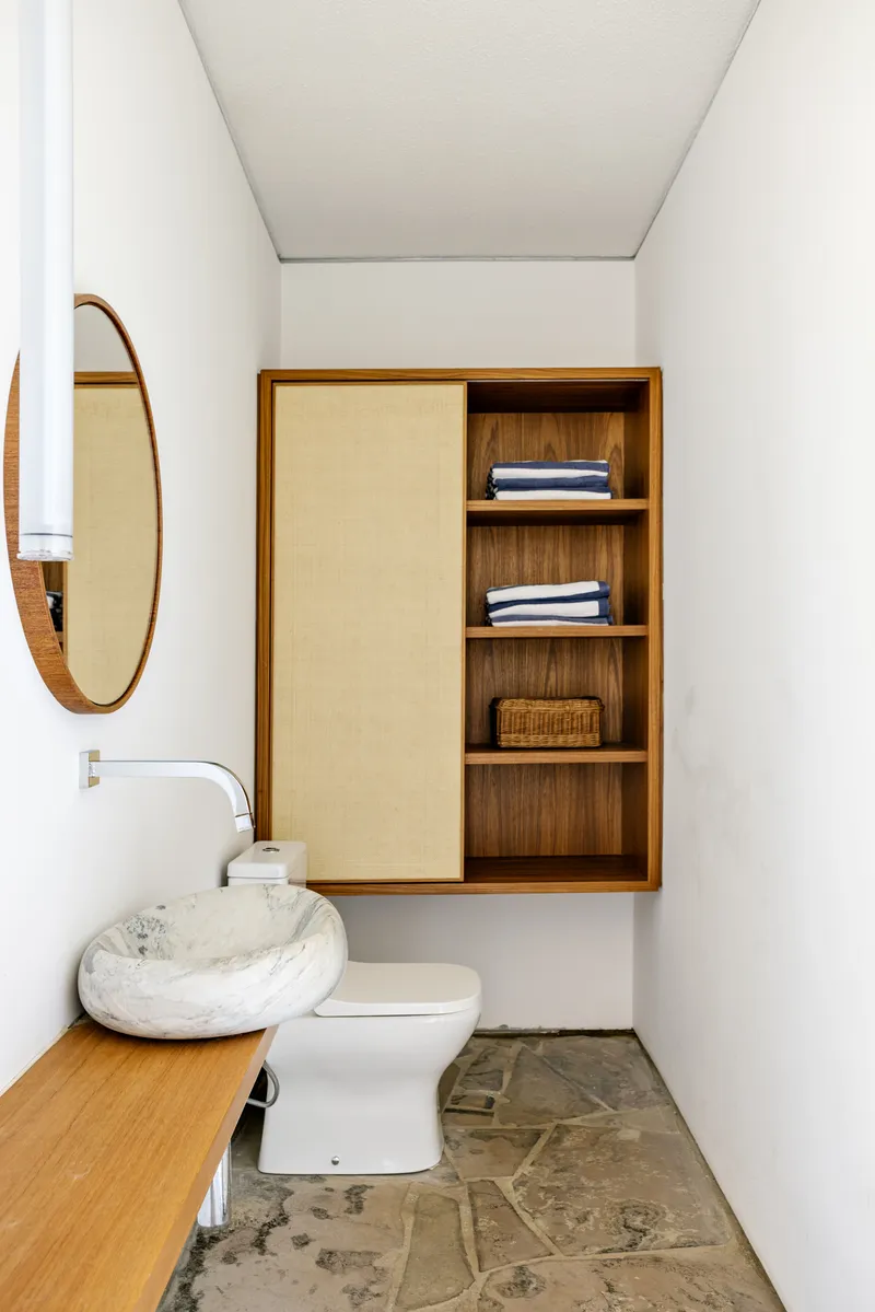 Compact bathroom with wall-mounted timber cabinet and stone vessel sink on timber vanity