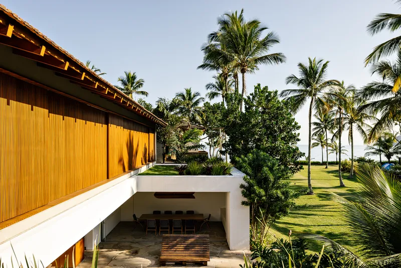 Upper terrace with vertical timber cladding overlooking a sunken outdoor dining area surrounded by palms