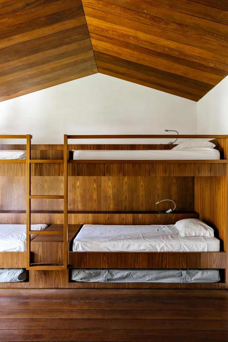 Built-in timber bunk beds beneath a gabled ceiling lined with horizontal wood planks