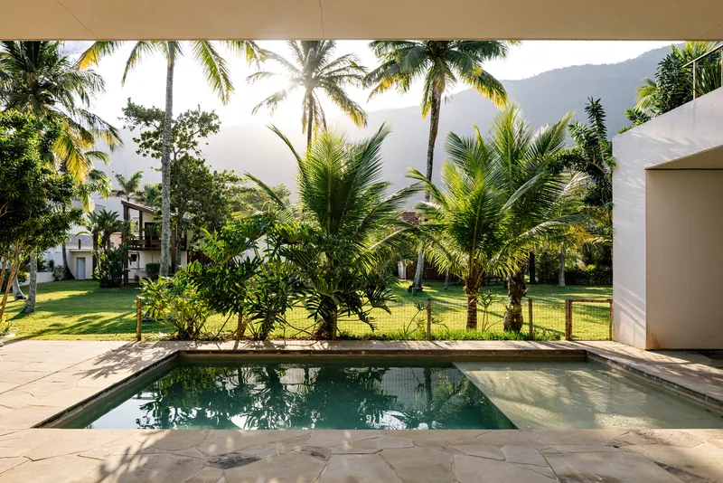 Rectangular pool with stone paving and view of palm grove and distant hills in afternoon light