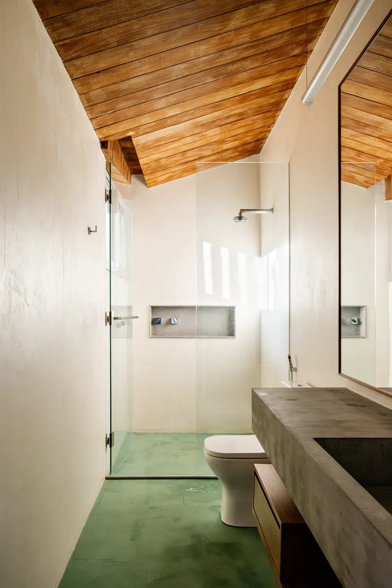 Bathroom with green polished concrete floor, exposed timber ceiling, and recessed shower niche