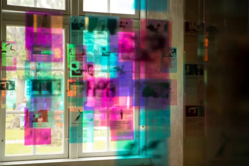 Layered translucent colored panels mounted on windows creating overlapping magenta and cyan reflections