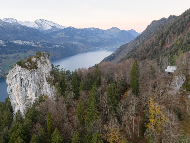 Distant view of the roofline against mountain peaks and a lake valley in late afternoon light