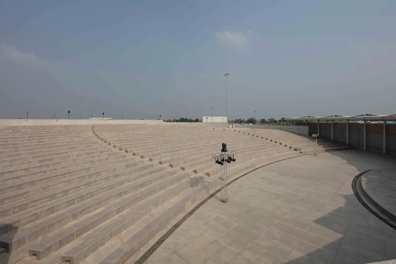 Wide view of curved amphitheatre seating with stone steps descending toward a central platform under clear sky