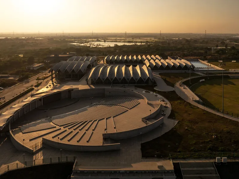 Aerial view of the repeating sawtooth rooflines and circular amphitheater at dusk with wetlands beyond