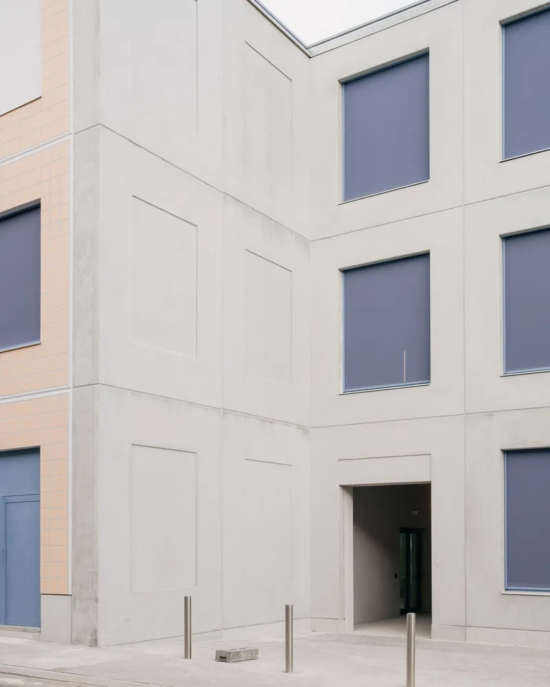 Corner detail of precast concrete panels with recessed doorway and steel bollards