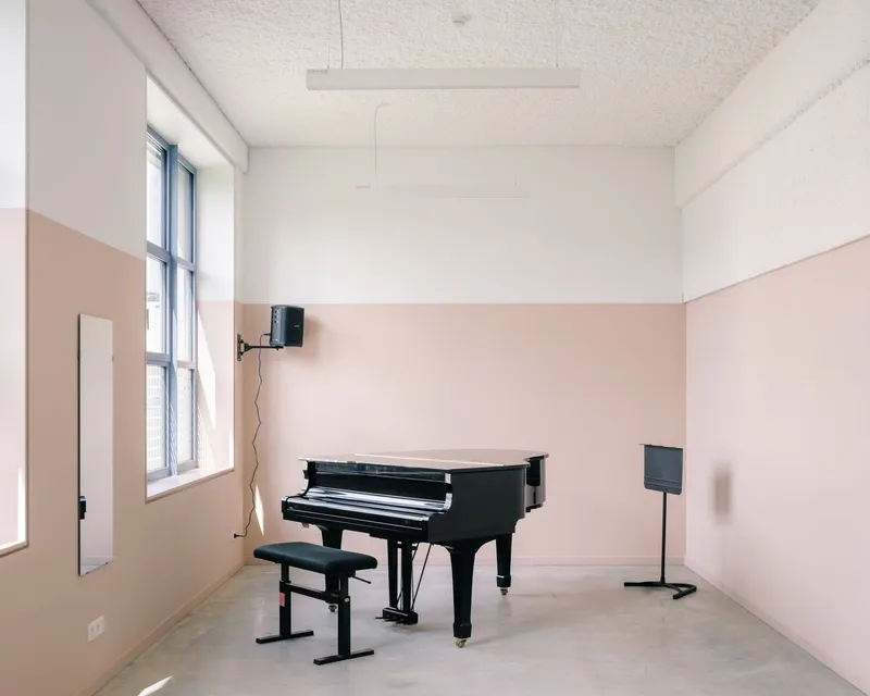 Music practice room with peach wainscoting and grand piano in daylight