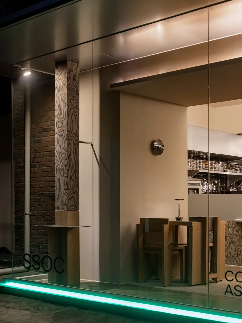 Glass entrance with wood-grain panels and green floor lighting at the base