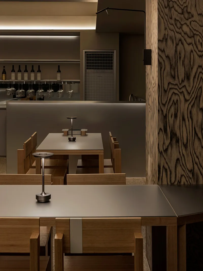 Interior view of dining tables with wood-grain column and backlit service counter beyond