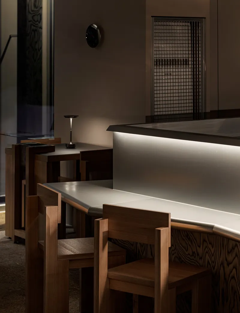 Oak seating adjacent to backlit counter with wire mesh screen in the background