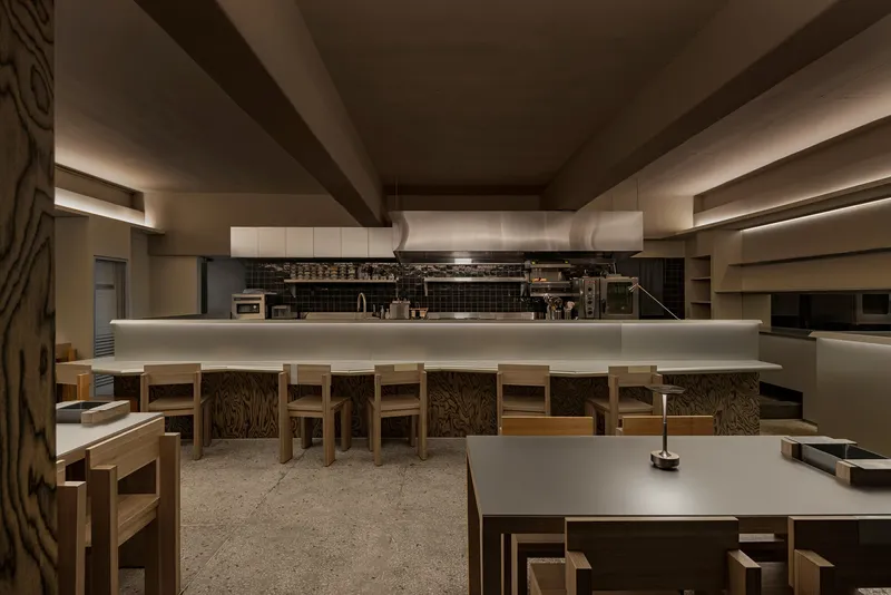 Interior restaurant dining area with timber furniture and backlit counter beneath exposed ceiling beams
