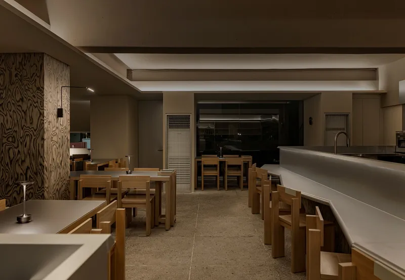 Interior view across terrazzo flooring showing timber seating and wood-paneled column at night