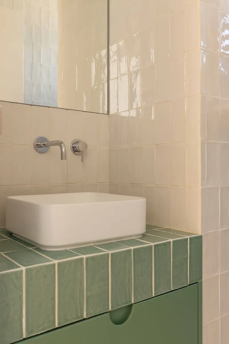 White rectangular basin on a green tiled countertop with wall-mounted chrome faucet