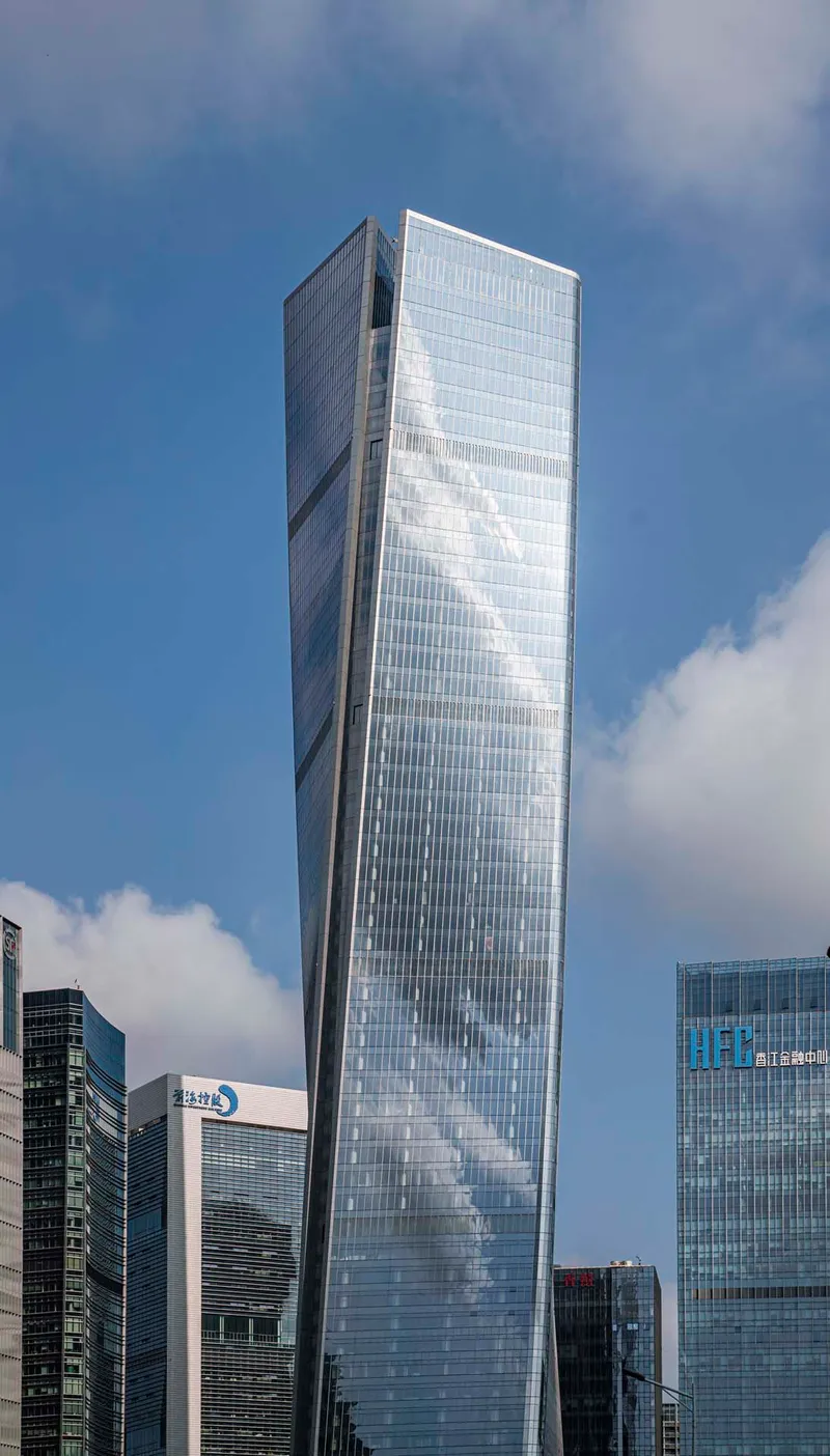 Angled facade of the glass tower showing diagonal structural bracing pattern against passing clouds