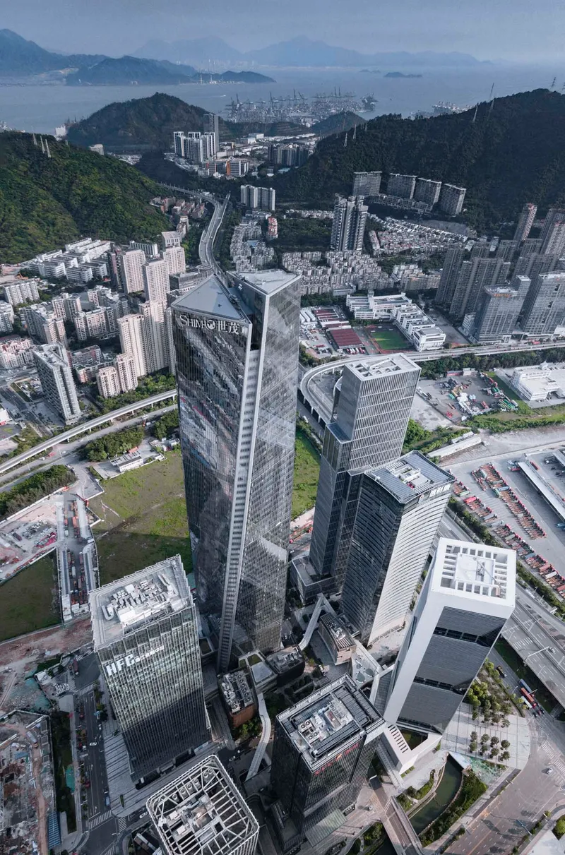 Aerial view of the twisted tower complex surrounded by hillside housing and distant harbor