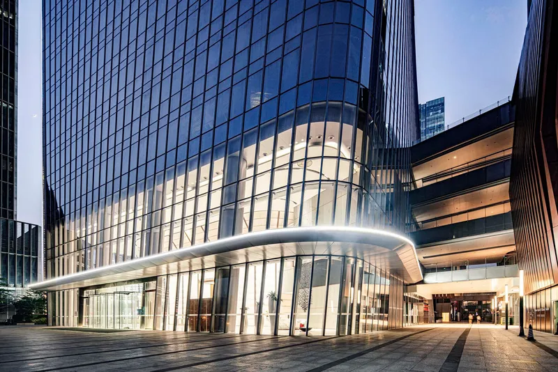 Ground-level entrance with illuminated glass lobby and cantilevered canopy at dusk