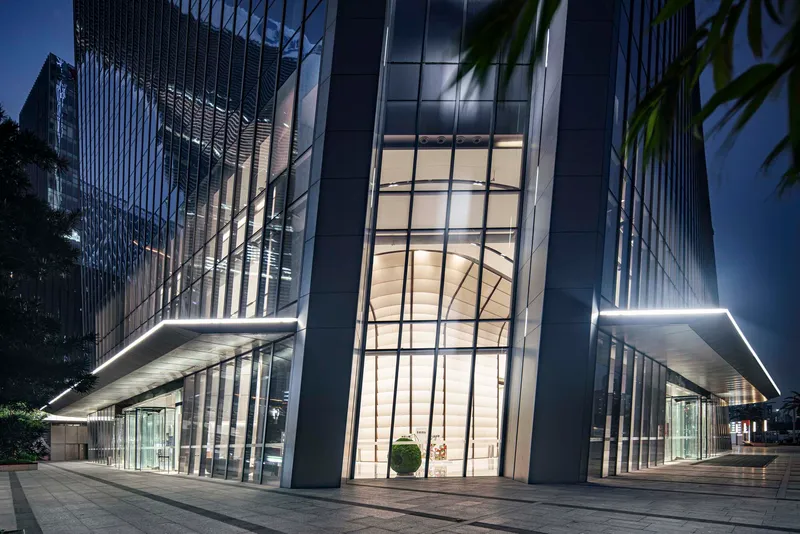 Nighttime view of the illuminated entrance lobby with floating canopy and glass towers above