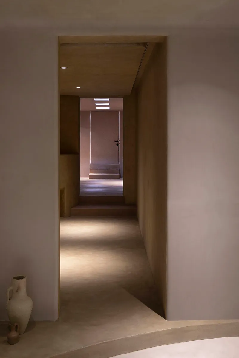 Sequence of thresholds leading to a backlit door at the end of a long corridor