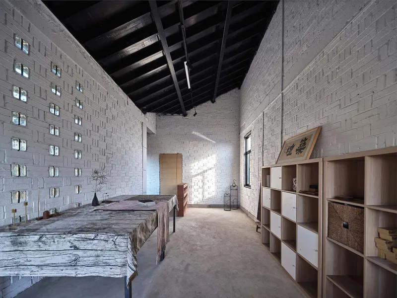 Bedroom with perforated white brick walls and exposed timber ceiling beams in afternoon light