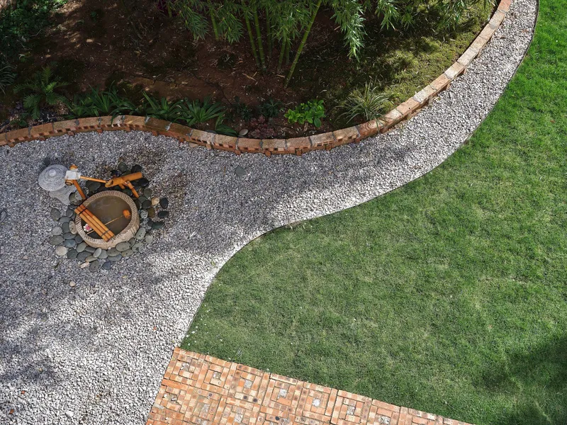 Aerial view of curved gravel pathways separating lawn and planted beds with bamboo and a central fire pit