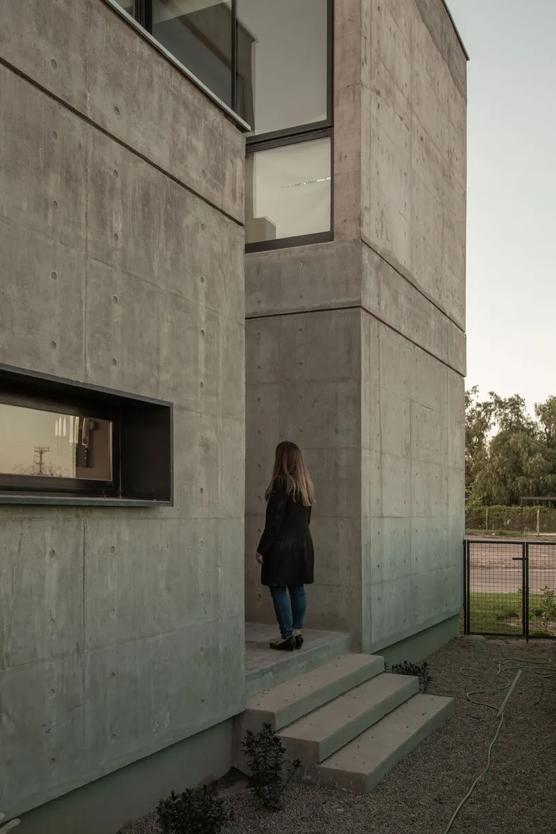 Concrete entry steps with a person approaching the recessed doorway in overcast light