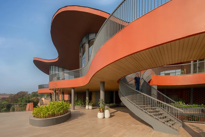Ground-level view of the terracotta-clad canopy and spiraling staircase with vertical metal louvres