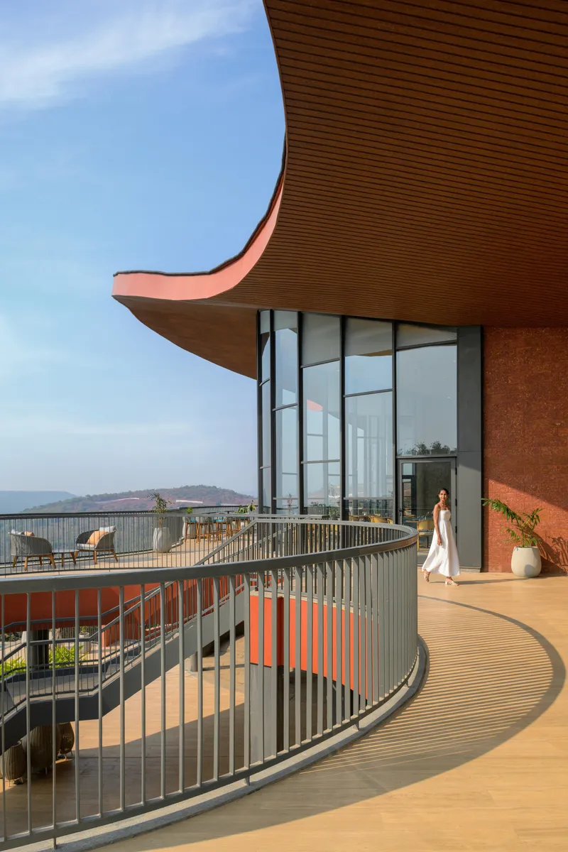Curved timber soffit with orange trim overhanging a terrace with vertical metal railing