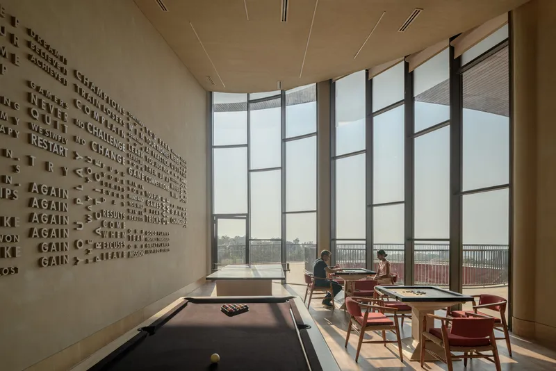 Recreation room with raised lettering wall and floor-to-ceiling gridded windows overlooking a terrace