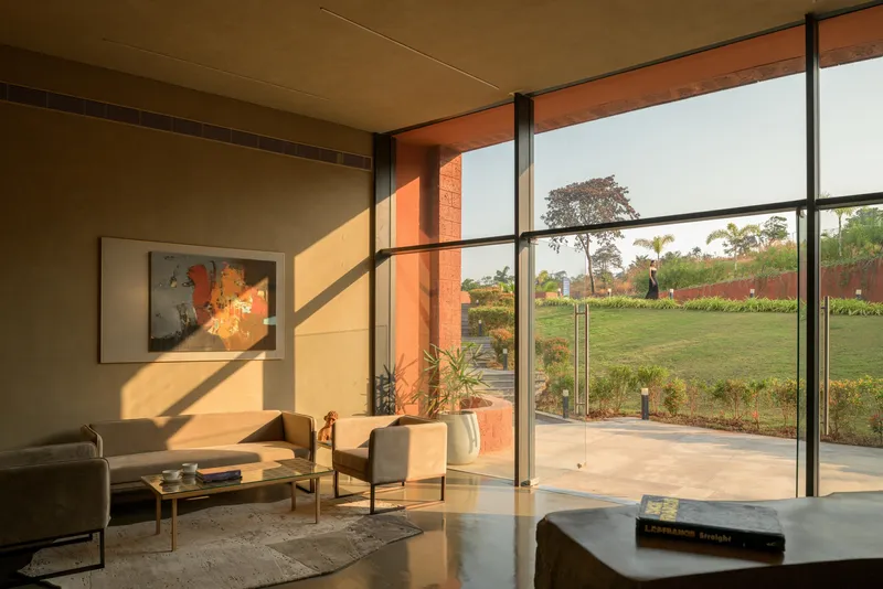 Living area with floor-to-ceiling glass doors framing a planted lawn in warm afternoon sun