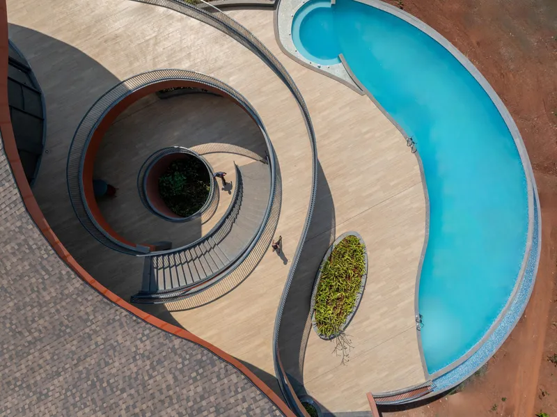 Aerial view of spiral staircase and curved swimming pool with planted beds on the deck