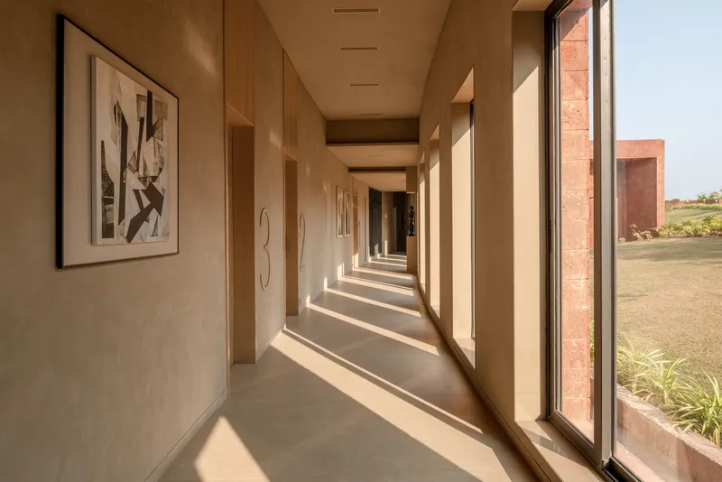 Gallery corridor with framed artworks and rhythmic sunlight patterns cast through window openings