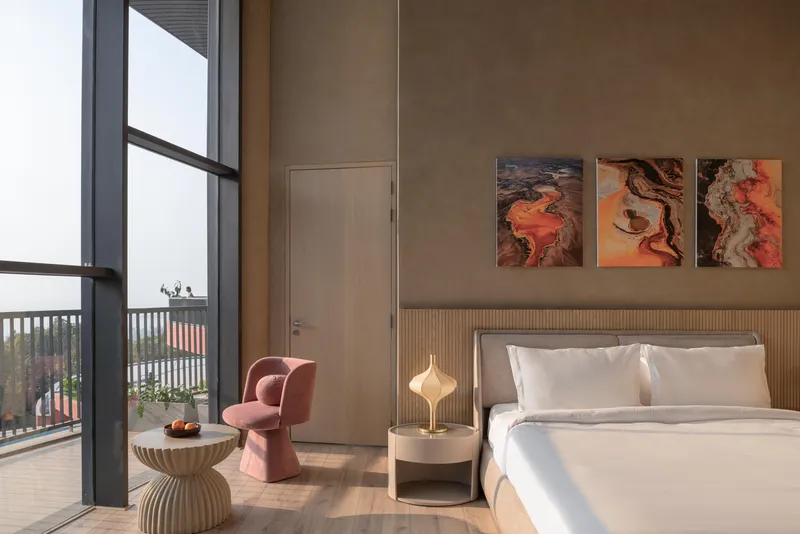 Double-height bedroom with floor-to-ceiling glazing overlooking a terrace and distant hills
