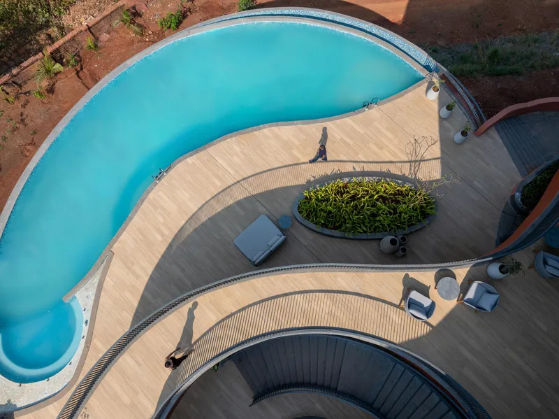Aerial view of the curved pool deck with planted island and a figure walking